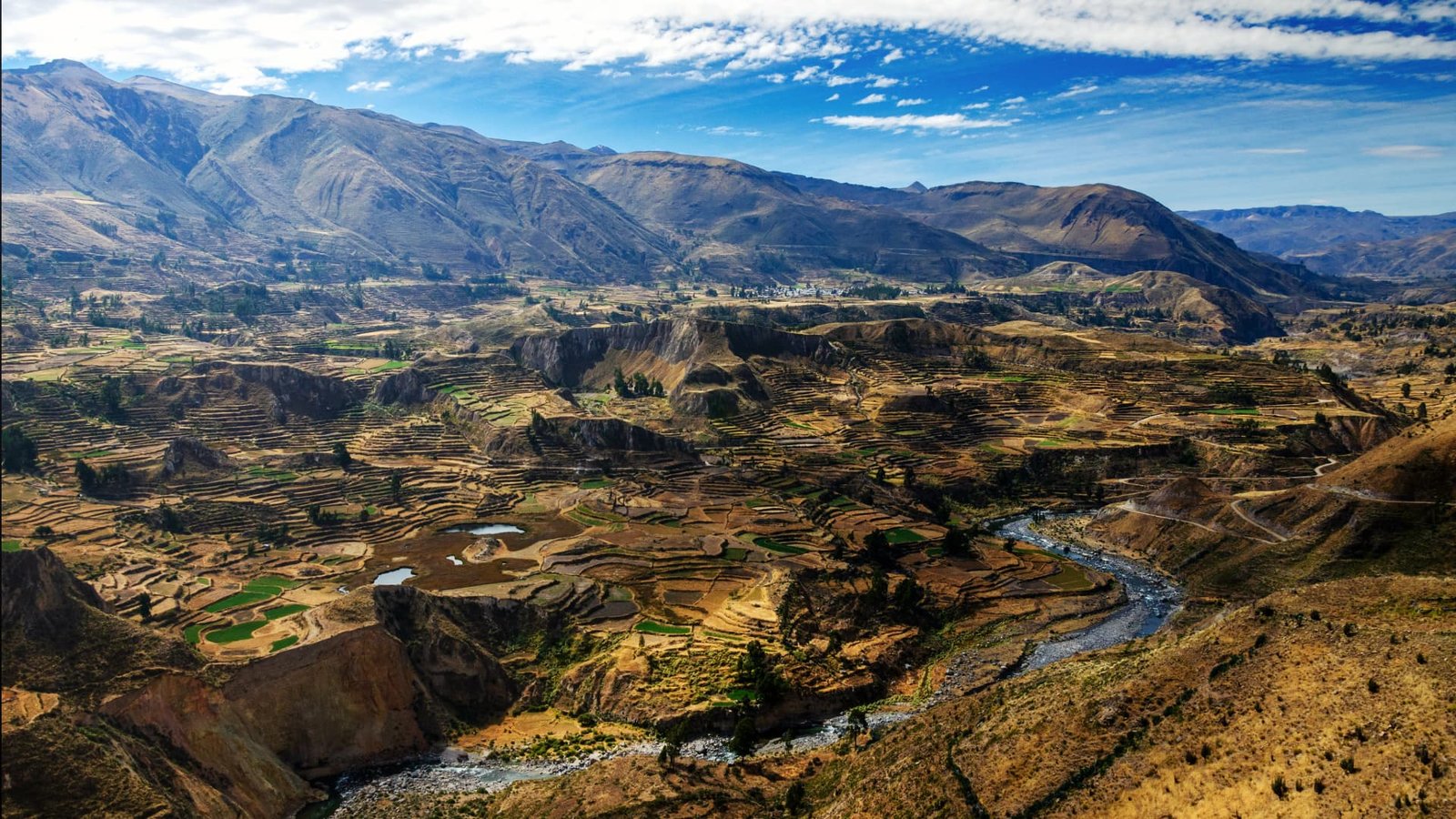 Paisaje de mesetas amarillentas con un río que corta el valle en la parte inferior bajo un cielo azul.