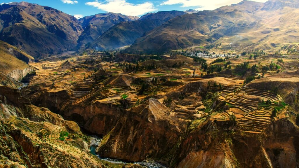 Vista cenital de la profundidad del Cañón del Colca con el río serpenteando al fondo entre montañas.