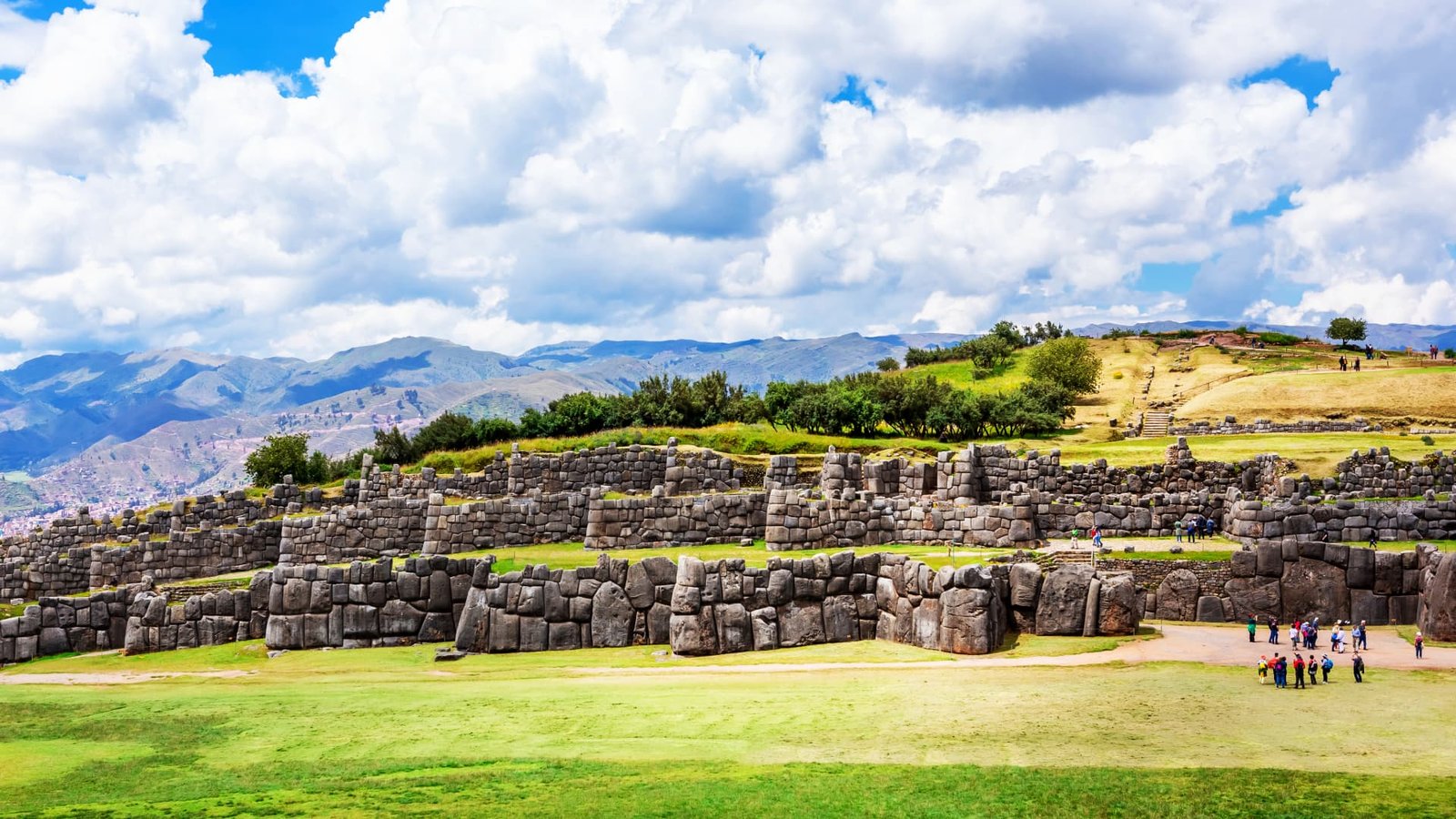 Estructuras de piedra con canales de agua y fuentes rituales incas rodeadas de vegetación.