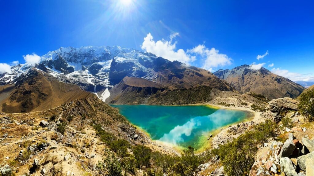 Vista de la Laguna Humantay reflejando el cielo azul con montañas nevadas de fondo.