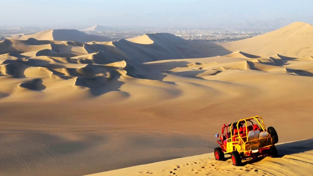 Buggy de arena rojo recorriendo las inmensas dunas del desierto de Ica cerca del oasis de Huacachina.