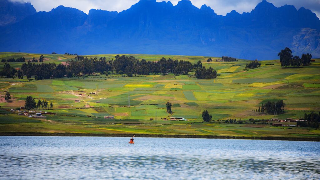 Praderas verdes y montañas nevadas bajo un cielo azul en Perú.