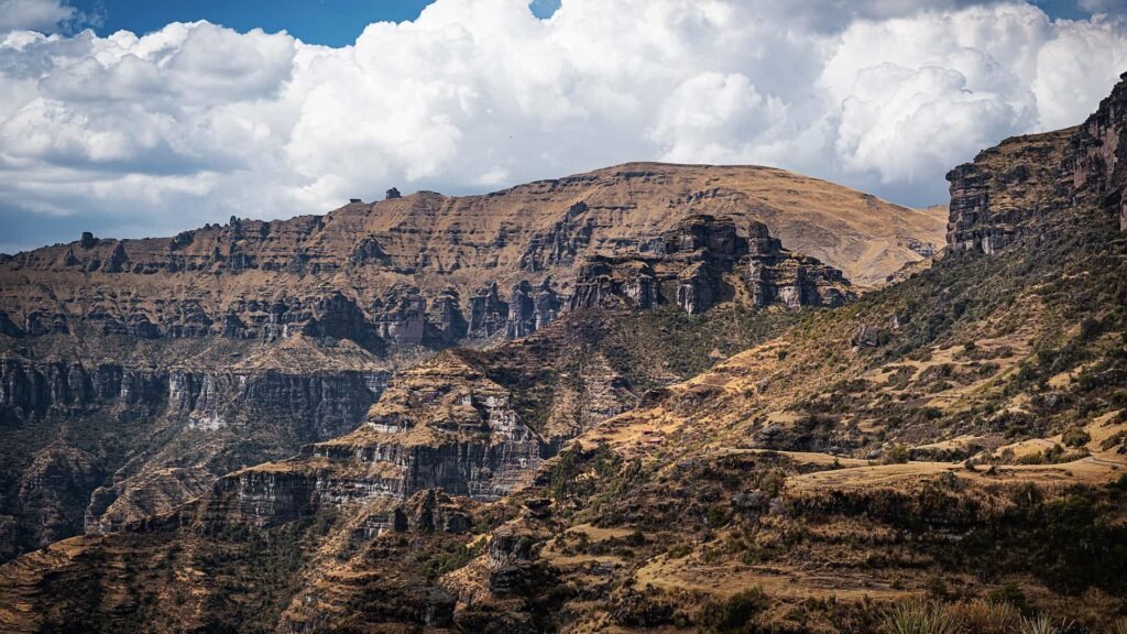 Paredes de roca estratificada y montañas escarpadas en el camino a Waqrapukara