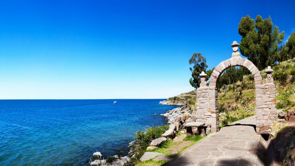 Camino de piedra junto al borde del Lago Titicaca bajo un cielo despejado.