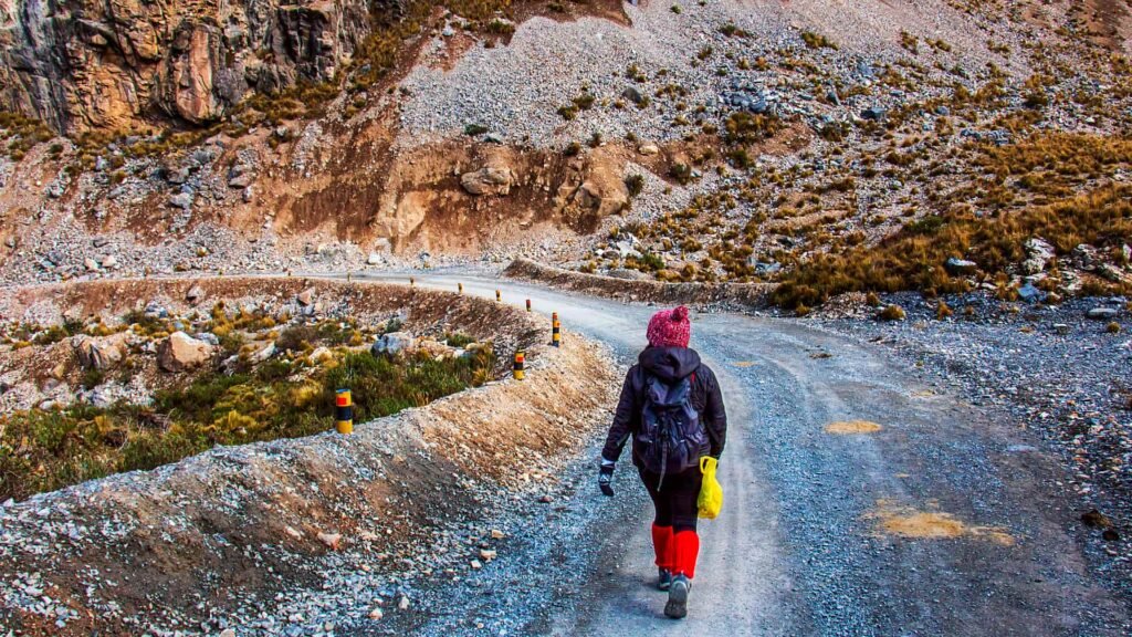 Mujer con mochila caminando por sendero de montaña en Huaraz.