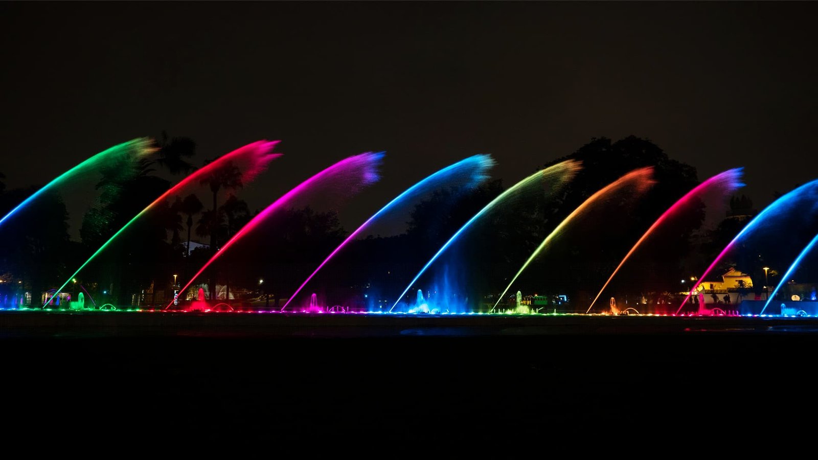 Chorros de agua en forma de arco iluminados con colores del arcoíris.