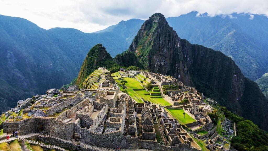 Estructuras principales de la ciudadela de Machu Picchu con la montaña Huayna Picchu al fondo bajo un cielo azul.