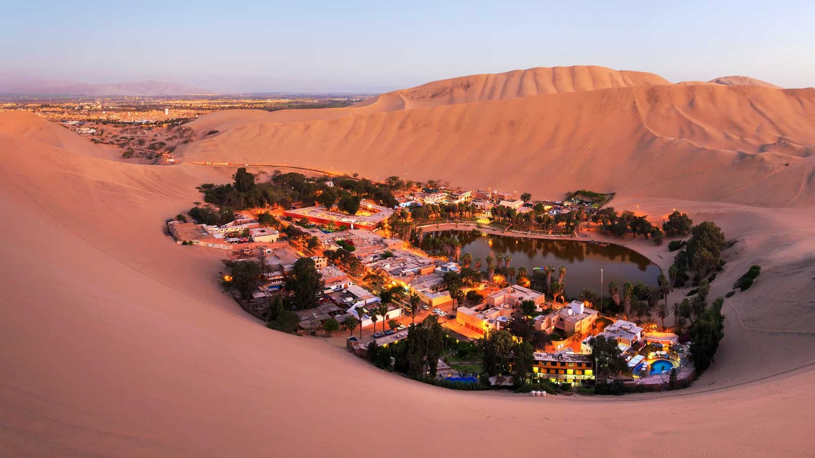Vista aérea nocturna iluminada del Oasis de la Huacachina.